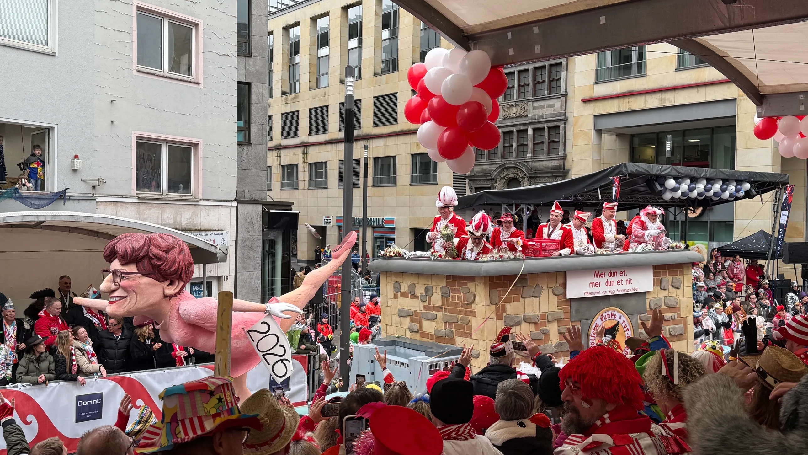 Wagen der Roten Funken im Rosenmontagszug 2026 mit der Aufschrift „Mer dun et, mer dun et nit“ und einer Persiflage-Figur, dahinter der Prinzenwagen